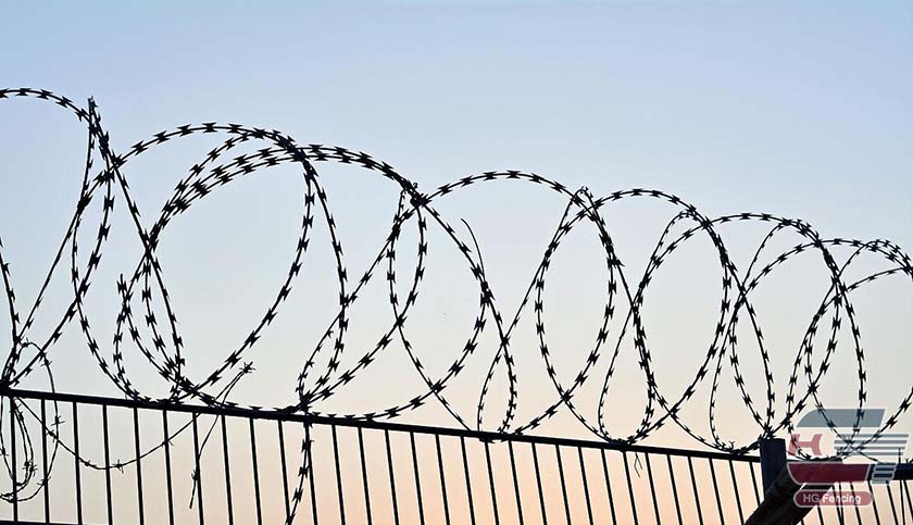 concertina wire mounted on top of the fence