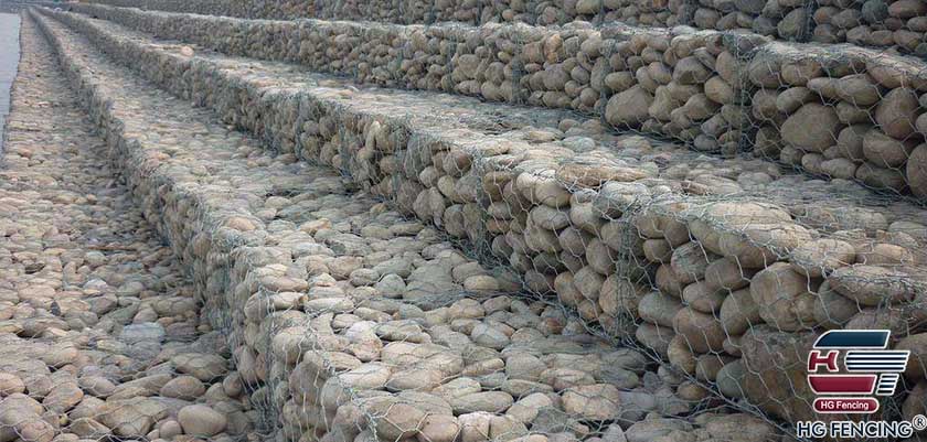 Hexagonal gabion basket filled with stones, used on riverbanks to prevent floods from scouring the banks.